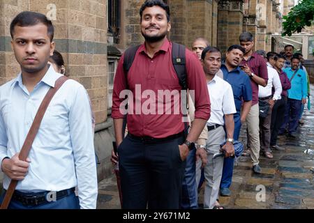 Männliche Pendler stehen in einer geordneten Buswarteschlange vor dem Chhatrapati Shivaji Maharaj Terminus in Mumbai, Maharashtra, Indien Stockfoto