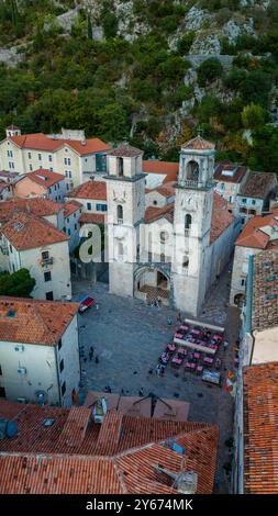 Im Herzen von Kotor, Montenegro, erheben sich historische Türme über bezaubernden Terrakotta-Dächern, während belebte Cafés die Plätze darunter füllen. Die Szene fängt das Wesen dieser malerischen Küstenstadt ein. Stockfoto