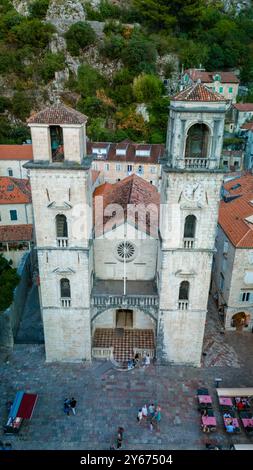 Besucher bewundern die atemberaubende Architektur und die bezaubernden Dächer von Kotor, Montenegro, während das Sonnenlicht wunderschöne Schatten wirft und eine malerische Atmosphäre in dieser historischen Küstenstadt schafft. Stockfoto