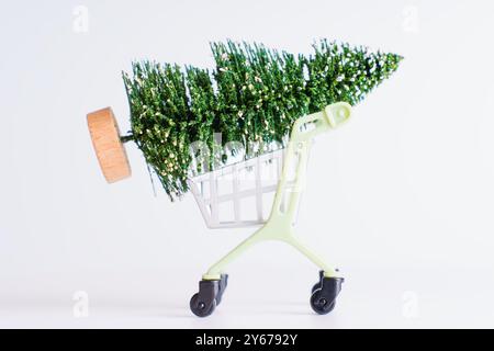 Einkaufswagen mit Weihnachtsmotiv und Miniatur-Weihnachtsbaum, ideal für festliche Dekorationen und saisonale Marketingkonzepte. Stockfoto