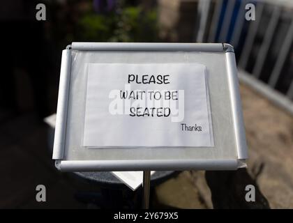 Bitte warten Sie, bis Sie Platz haben - Restaurant-Schild in Großbritannien Stockfoto