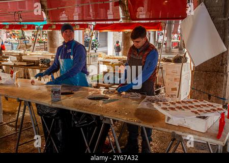 Fischhändler bereiten Fisch auf dem Rialto Fischmarkt in der San Polo Sestiere von Venedig, Italien zu Stockfoto