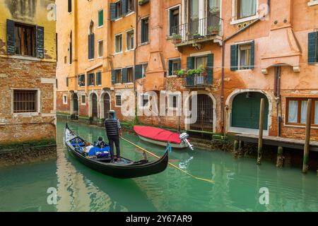 Ein Gondolierer fährt seine Gondelbahn entlang eines rio de San Lio, einem Kanal im Castello Sestiere in Venedig, Italien Stockfoto