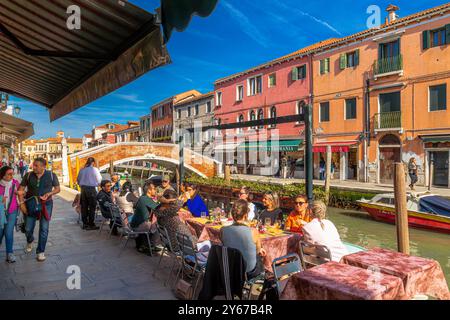 Die Leute genießen das Mittagessen in einem Restaurant am Kanal auf der Fondamenta Manin neben dem Rio dei vetrai, einem Kanal auf der Insel Murano in der Nähe von Venedig, Italien Stockfoto