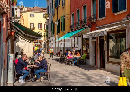 Leute, die vor Restaurants sitzen und Essen und Getränke entlang der Calle Larga in der Nähe von Campo S. Giacomo in der Santa Croce Sestiere von Venedig, Italien, genießen Stockfoto