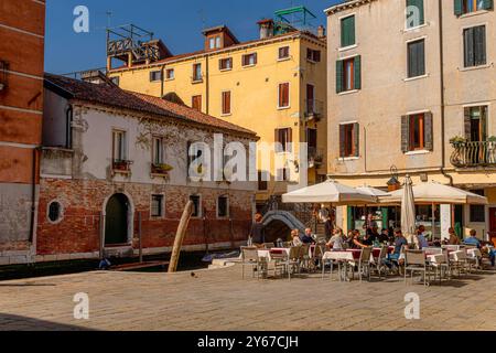 Leute sitzen vor dem Il Refola, einem Restaurant neben einem Kanal in Campo San Giacomo dell'Orio im Santa Croce Sestiere von Venedig, Italien Stockfoto