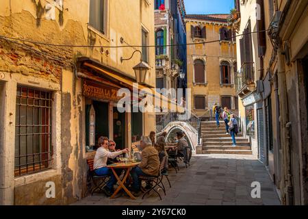 Gäste, die draußen sitzen, genießen Speisen und Getränke in der Osteria La Zucca in der Nähe von Ponte del Megio im Santa Croce Sestiere von Venedig, Italien Stockfoto