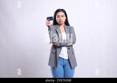 Schöne junge Bürofrau asien pouting Arme halten Debitkreditkarte, die grauen Anzug trägt und isoliert auf weißem Hintergrund steht. Für Unternehmen, l Stockfoto