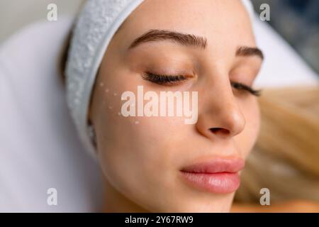 Schöne entspannte Frau im Kosmetikschrank, die Anti-Falten-Injektionen auf die Wangenknochen erhält, liegend mit geschlossenen Augen im Schönheitssalon Stockfoto