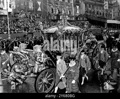 Königin Elisabeth II. Trägt die Imperial State Crown und Prinz Philip, der Duke of Edinburgh, in der Staatskutsche, als sie während der Prozession von Westminster Abbey zum Buckingham Palace nach der Krönung in den East Carriage Drive of Hyde Park von Piccadilly umsteigen. Dahinter sind die riesigen Menschenmassen, die den strömenden Regen beobachteten. Juni 1953 Stockfoto
