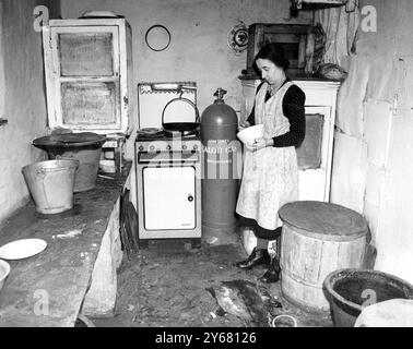 Mrs. Peters ging 1916 mit ihrem Mann auf die Farm. Jetzt eine Witwe, sie ist 59, sieht aber viel jonger aus. Mit Hilfe ihrer beiden Brüder schafft sie es sehr geschickt. Das ist ihre Küche - der einzige moderne Komfort ist das Flaschengas und der Herd - der ungefähr 13 Meilen gebracht wird, wenn eine neue Flasche benötigt wird. - 17. Dezember 1950 Stockfoto