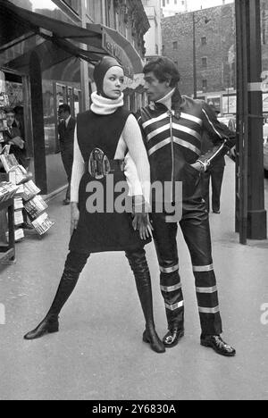 Therese und Gilles Modeloutfits aus Pierre Cardins Herbst-Winter-Kollektion, 1968. Sie trägt einen schwarzen Filzpullover über einem Schildkrötenkragen aus weißer Wolle mit langen Stiefeln und einem schwarzen Lederhelm. Er trägt einen schwarzen Ledermantel mit großen Reißverschlüssen auf der Vorderseite und den Ärmeln, die mit silbernen Streifen verziert sind. Paris, Frankreich - 26. Juli 1968 Stockfoto