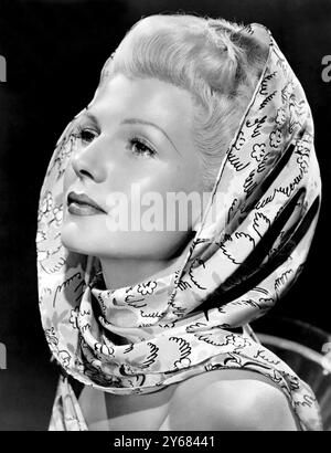 Getragen von Rita Hayworth auf ihrem neuen Columbia-Bild The Lady from Shanghai und wunderschön aus feinster Seide gefertigt, ergänzt dieser mehrfarbige Schal in Grün, Kastanienbraun und Bernstein Ritas topasblonden Coiffure. Februar 1948. Stockfoto