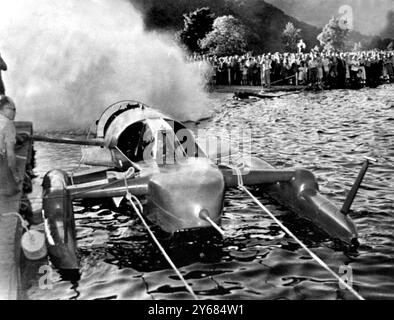 Lake Ullswater, Cumberland: Donald Campbell sitzt im Cockpit seines Turbo-Jet-getriebenen Bluebird und versucht ihre Motoren, während er vor Anker steht. Campbell, der während der Tests eine inoffizielle Geschwindigkeit von 185 km/h mit Bluebird erzielte, ist bereit für einen Versuch auf den Weltrekord für Wassergeschwindigkeiten - gehalten von Amerika mit 178,497 km/h. Bei diesem Test wurde eine 100 Meter lange Sprühwolke aufgeschossen, die die Beobachter durchnässt hat. Juli 1955 Stockfoto