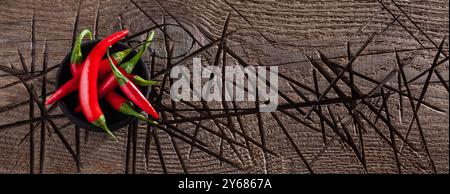 Heiße rote Chilischote in einer schwarzen Schüssel auf einem alten Holztisch Stockfoto
