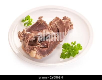 Gekochtes Rinderherz auf weißem Teller mit Petersilie. Das Nebenprodukt der diätetischen Nahrung hat einen niedrigen Kaloriengehalt. Isoliert auf weißem Hintergrund Stockfoto
