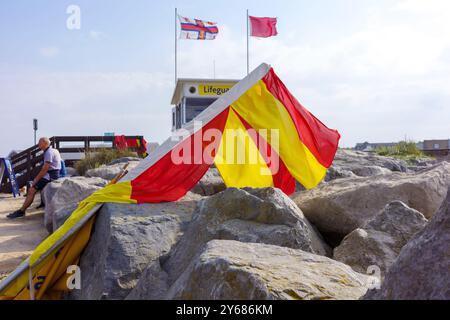 New Brighton, Wallasey, Großbritannien, 21. September 2024: helle Warnfahnen an einer Rettungswache an einem felsigen Strand. Stockfoto