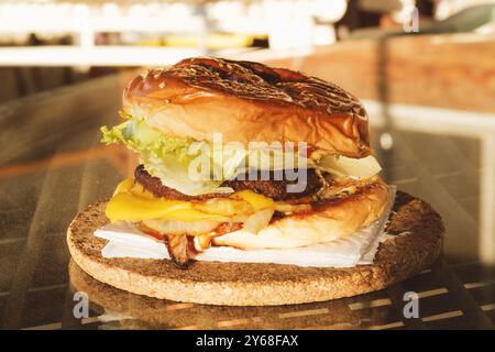 Ein Nahaufnahme eines hausgemachten Burgers mit frischem Salat, geschmolzenem Käse, gegrillten Zwiebeln und einem saftigen Rindfleisch-Patty in einem Sesambrötchen Stockfoto