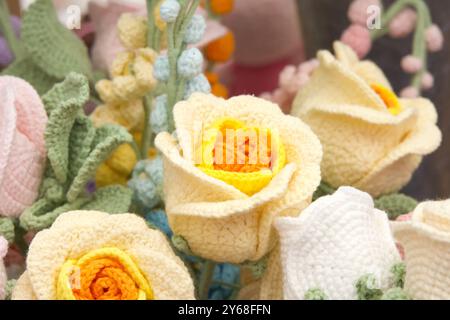 Nahaufnahme eines Straußes wunderschöner handgefertigter Häkelblumen. Gelbe und orangene Rosen Stockfoto