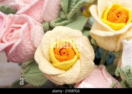 Nahaufnahme eines Straußes wunderschöner handgefertigter Häkelblumen. Gelbe und orangene Rosen Stockfoto