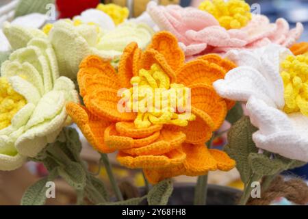 Nahaufnahme eines Straußes wunderschöner handgefertigter Häkelblumen. Orangefarbene und gelbe Blüte. Stockfoto