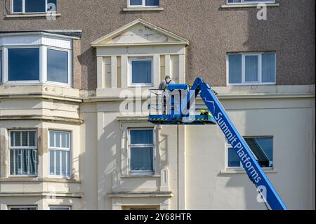 Arbeiter an einem Kirschpflücker/hydraulischen Hubwerk/hydraulischen Hebebühne bei der Wartung einer Gebäudefassade, Schottland, Großbritannien, Europa Stockfoto