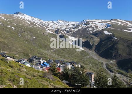 Ein Bergdorf mit bunten Häusern in einer schneebedeckten Berglandschaft unter klarem Himmel, links Pico del Veleta, Veleta Gipfel, Dorf Sierra Nevada, Gi¿½ Stockfoto