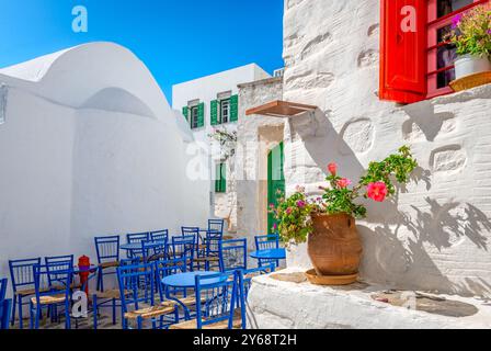 Café im Freien im Dorf Hora auf der Insel Amorgos, Kykladen, Griechenland. Enge Gassen mit weiß getünchten Häusern, die mit Blumentöpfen dekoriert sind. Stockfoto