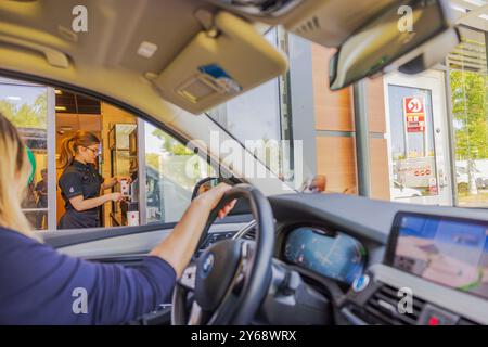 Drive-Thru bei McDonald's, Server übergibt Bestellungen an Kunden im Auto. Schweden. Stockholm. Stockfoto