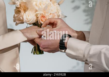 Romantische Hochzeitszeremonie, bei der Braut und Bräutigam die Ringe vor einem weichen floralen Hintergrund austauschen. Stockfoto