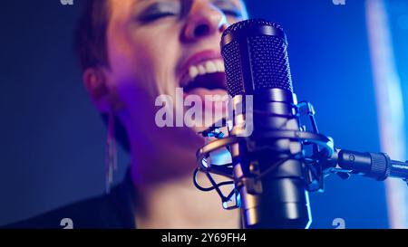 Der talentierte Rockkünstler tritt live mit kraftvollem Gesang und kühner Energie auf. Trendige rebellische Musikerin, die alternative Musik auf der Bühne singt, Grunge-Superstar zeigt ihr Können. Nahaufnahme. Kamera A.. Stockfoto