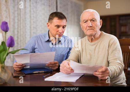 Älterer Mann, der Dokumente mit einem erwachsenen Sohn bespricht Stockfoto