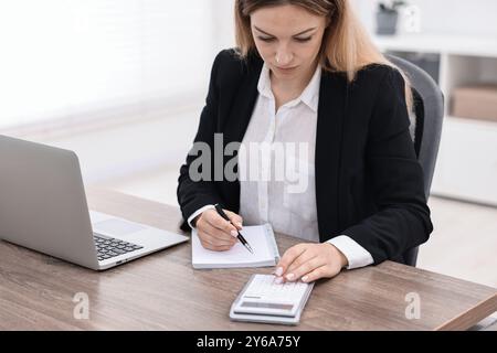 Banker mit Notizbuch am Holztisch im Büro Stockfoto