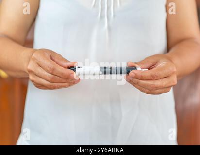 Frauen drehen den Knopf am Ende des Insulinpens und stellen die korrekte Insulindosis für die Injektion ein. Skalieren zu Hause. Stockfoto