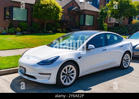 Seattle, WA, USA - 3. Juli 2024: tesla Model 3 weiß in der Nähe eines Luxushauses. Stockfoto