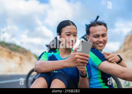 Radfahrerpaar, das Telefon mit Zeigegegeste benutzt Stockfoto