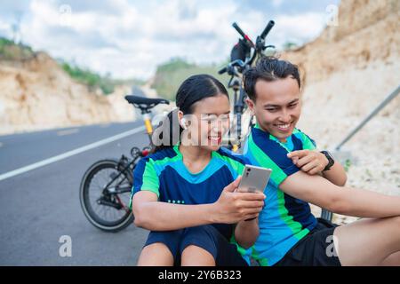 Weibliche Bikerin, die das Telefon hält, und männliche Bikergeste Stockfoto