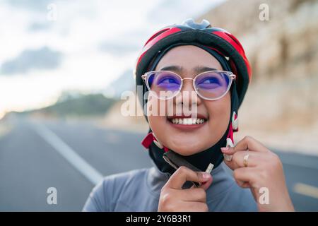 Hijab-Biker, der einen Helm für ein sicheres Fahrrad aufsetzt Stockfoto