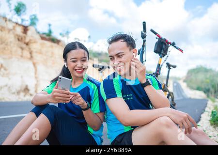 Weibliche und männliche Biker verwenden Kopfhörer, die ihre Telefonverbindung teilen Stockfoto