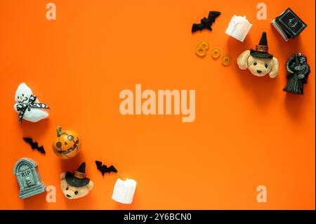 Halloween-Hintergrund mit niedlichen Puppen und kleinen Dekorationen auf orangem Hintergrund. Minimales Konzept. Stockfoto