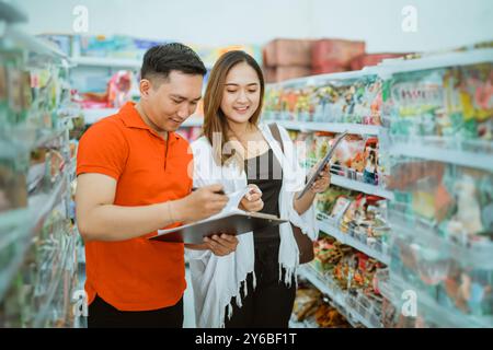 Männlicher Arbeiter mit Klemmbrett und weiblicher Besitzerin mit Tablet im Supermarkt Stockfoto