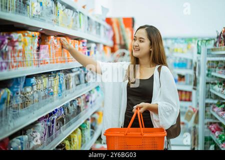 Attraktive asiatische Frau, die sich die Artikel in den Regalen anschaut Stockfoto