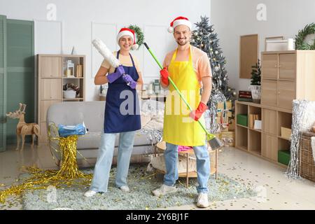 Junge Hausmeister in Santa-Hüten mit Putzmitteln nach Neujahrsfeier Stockfoto