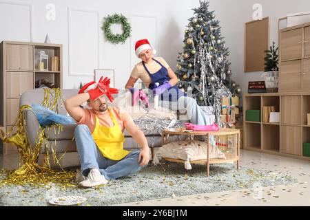 Müde Hausmeister in Santa Hats Reinigungsraum nach Neujahrsfeier Stockfoto