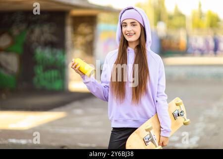 Teenager-Mädchen mit Sprühfarbe und Skateboard draußen Stockfoto