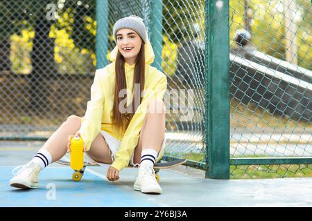 Teenager-Mädchen mit Sprühfarbe und Skateboard auf dem Sportplatz Stockfoto