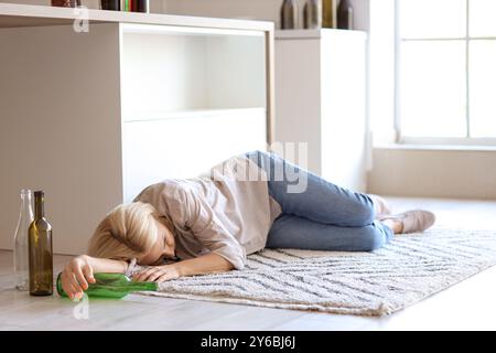 Betrunkene reife Frau, die zu Hause auf dem Boden liegt. Der Begriff des Alkoholismus Stockfoto