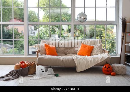 Stilvolles Sofa mit Discokugel und Halloween-Dekoration in der Nähe des Fensters zu Hause Stockfoto