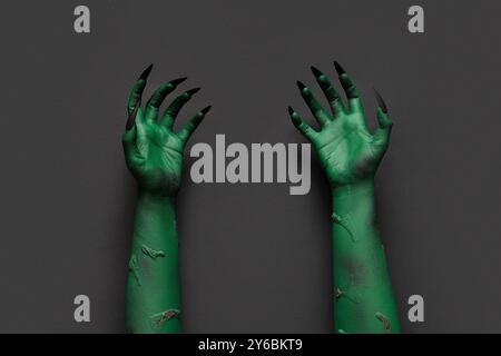 Grüne Hände der Hexe mit Krallen auf schwarzem Hintergrund. Halloween-Feier Stockfoto