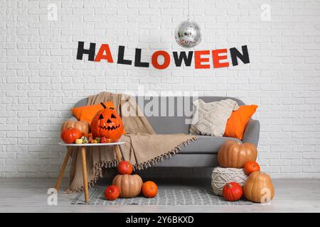 Das Innere des stilvollen Zimmers mit Sofa, Kürbissen und Diskokugel ist für die Halloween-Party dekoriert Stockfoto